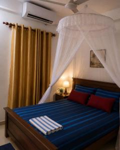 a bedroom with a bed with a canopy at SunBeachHouse in Weligama +5 photos