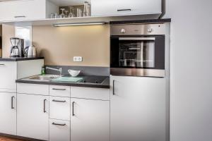 a kitchen with white cabinets and a sink at Central Suites in Greifswald