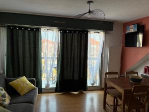 a living room with a table and two large windows at Studio centre ville - 5min de la plage in Neufchâtel-Hardelot