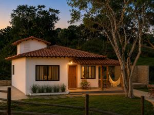 a small white house with a tree at Casa com Jacuzzi Charme Corumbá in Alexânia