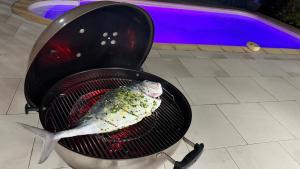 a fish cooking on a grill next to a grill at Studio piscine centre Gosier in Le Gosier