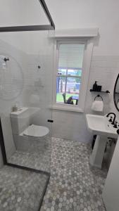a bathroom with a toilet and a sink and a window at The Foxman Cottage in Broke +22 photos