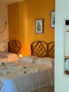 a bedroom with two beds and a yellow wall at Pousada Costa dos Corais in Mangaratiba