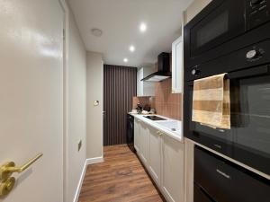 a kitchen with a black oven and a sink at Cozy Studio in Eccles - Salford, Manchester in Manchester