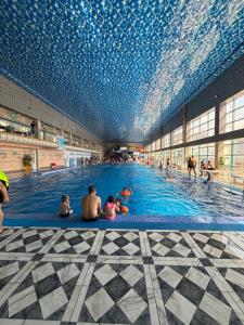 a large swimming pool with people sitting in the water at Версаль отель in Türkistan