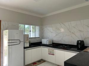 a kitchen with white counters and a white refrigerator at Chalés Sítio Frade in Martins