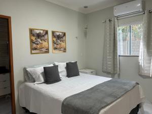 a white bedroom with a large bed with two pillows at Chalés Sítio Frade in Martins +6 photos