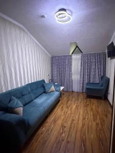 a living room with a blue couch and a chair at Версаль отель in Türkistan