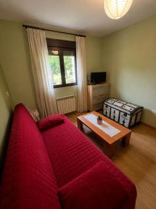 a living room with a red couch and a table at El Mensario in Campisábalos
