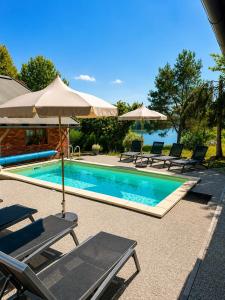 a swimming pool with chairs and umbrellas next to it at Lake House with a View in Šmartno v Rožni Dolini