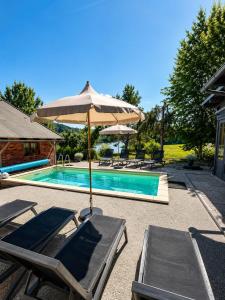 a swimming pool with an umbrella and lounge chairs next to it at Lake House with a View in Šmartno v Rožni Dolini