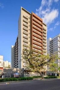 a tall building with a tree in front of it at Apê Brisa-5min consulado EUA-garagem in Porto Alegre
