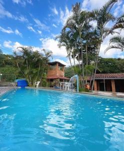 a large swimming pool in front of a house at Aconchego Caminho das Cachoeiras in Rio Acima