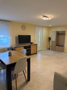 a living room with a table and a flat screen tv at Maison Charmante in Donges