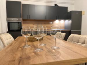 three wine glasses sitting on top of a wooden table at Garden View Apartment in Čapljina