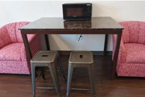 a table with a laptop on top of it with two stools at Del Playa Inn Oxnard Near Camarillo in Oxnard