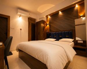 a bedroom with a large white bed with a wooden headboard at Hotel Prince Paradise in Patna
