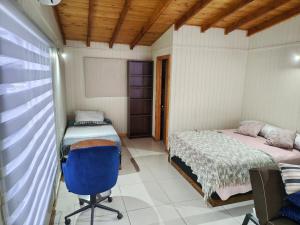 ein Schlafzimmer mit zwei Betten und einem blauen Stuhl in der Unterkunft dormitorio REST in Chaitén