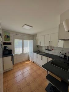 a kitchen with white cabinets and a tile floor at Casa Pont in Osséja
