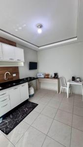 a kitchen with white cabinets and a table and a sink at Saif Economy Apart in Paranaguá