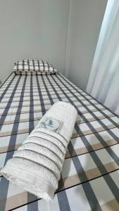 a bed with a white pillow on a checkered floor at Saif Economy Apart in Paranaguá