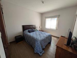 a bedroom with a bed and a television and a window at Departamento EMPRESARIAL cerca de zona industrial in Chihuahua