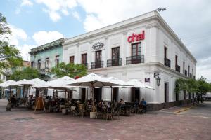 ein weißes Gebäude mit Tischen und Sonnenschirmen davor in der Unterkunft Del Carmen Concept Hotel Boutique by Chai in Guadalajara