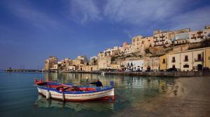 ein Boot, das im Wasser neben Gebäuden liegt in der Unterkunft La Chiusa Case Vacanze in Castellammare del Golfo