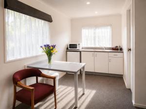 a kitchen with a table and a vase of flowers at Settlers Motor Lodge in Lower Hutt +14 photos