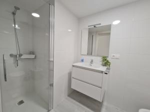 a white bathroom with a sink and a shower at Albergue EL CASTILLO in Sarria