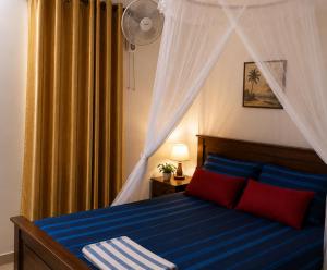 a bedroom with a bed with blue sheets and red pillows at SunBeachHouse in Weligama