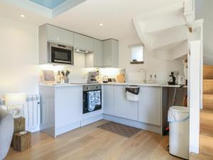 a kitchen with white cabinets and a stove top oven at Little Barn in Leek