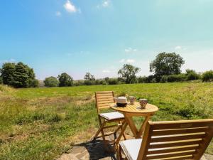 a wooden table and two chairs on a field at Little Barn in Leek