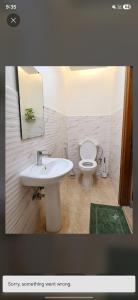 a bathroom with a white sink and a toilet at Hidden Villa in Al Ain