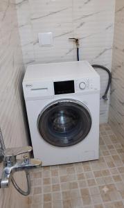 a white washing machine in a bathroom with a chair at Hidden Villa in Al Ain