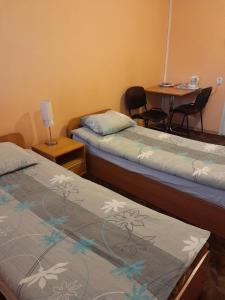 two beds in a room with a table and chairs at Pokoje Slomkowscy in Łódź