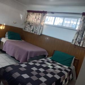 a bedroom with two beds and a window with curtains at Guesthouse Playa Chinchorro in Arica