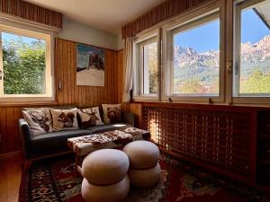 a living room with a couch and a table and windows at Ca' Scalinatella in Cortina dʼAmpezzo +29 photos