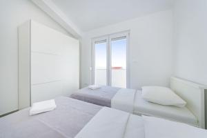 a white bedroom with two beds and a window at Apartment Paulo&Lorenco in Sveti Filip i Jakov