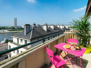 a balcony with a pink table and chairs on a balcony at Ibis Styles Rouen Centre Cathédrale in Rouen