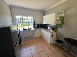 a kitchen with white cabinets and a tile floor at Stylish 1-Bed Cottage,Garden, Pool Secure Parking in Alberton