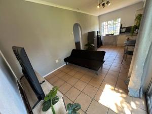 a living room with a black couch and a tiled floor at Stylish 1-Bed Cottage,Garden, Pool Secure Parking in Alberton