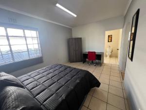 a bedroom with a bed and a desk in it at Stylish 1-Bed Cottage,Garden, Pool Secure Parking in Alberton