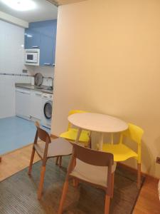 a kitchen with a table and two chairs and a table at Apartamentos Chevere Azul con Garaje in Oviedo