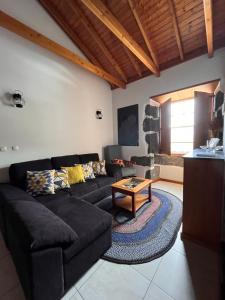 a living room with a black couch and a table at A Casa dos Meus Sonhos in Santo Amaro