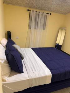 a bed with blue and white sheets and a window at The Cozy House in Estelí +3 photos