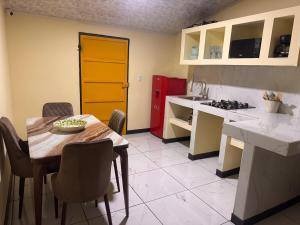 a kitchen with a table and chairs and a yellow door at The Cozy House in Estelí
