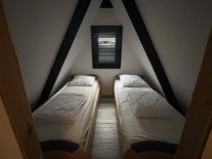 two beds in a attic room with a window at Dune & zee in Oostduinkerke +2 photos