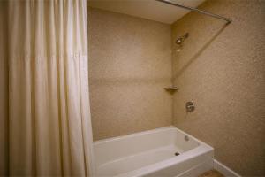 a bathroom with a tub and a shower curtain at Del Playa Inn Oxnard Near Camarillo in Oxnard