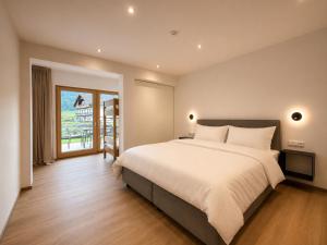 a bedroom with a large white bed and a window at BASE Achensee - Opening August 2026 in Achenkirch